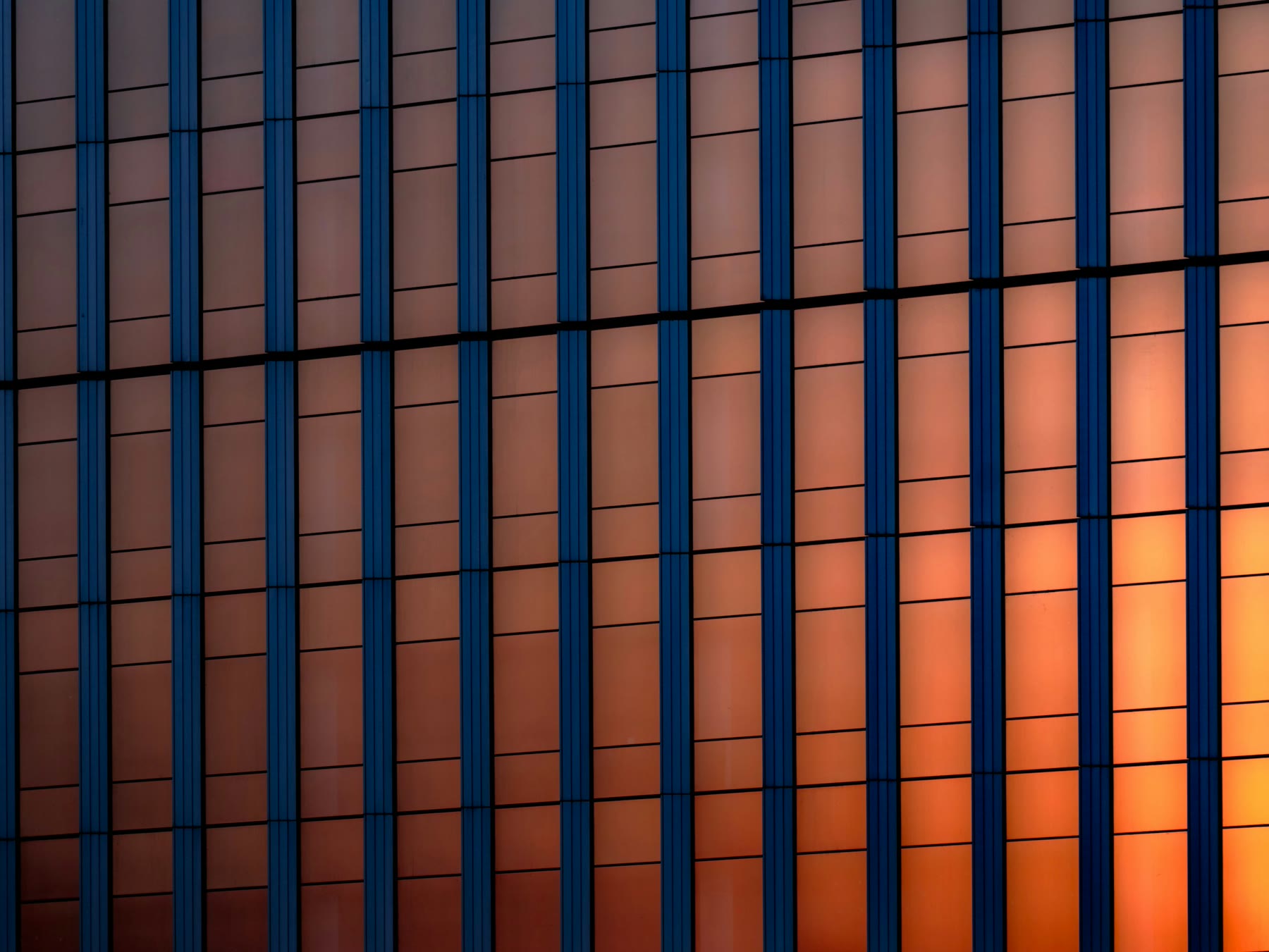 Fațadă curtain wall din sticlă cu reflexii calde de apus — detaliu elegant arhitectural